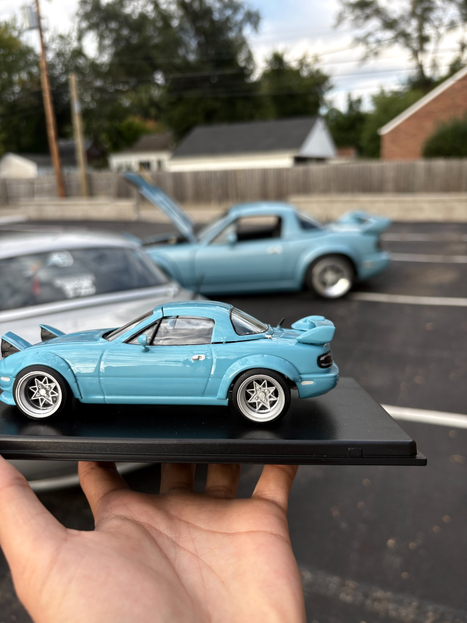 Project Blue Snow miniature displayed in front of the matching full-size Miata