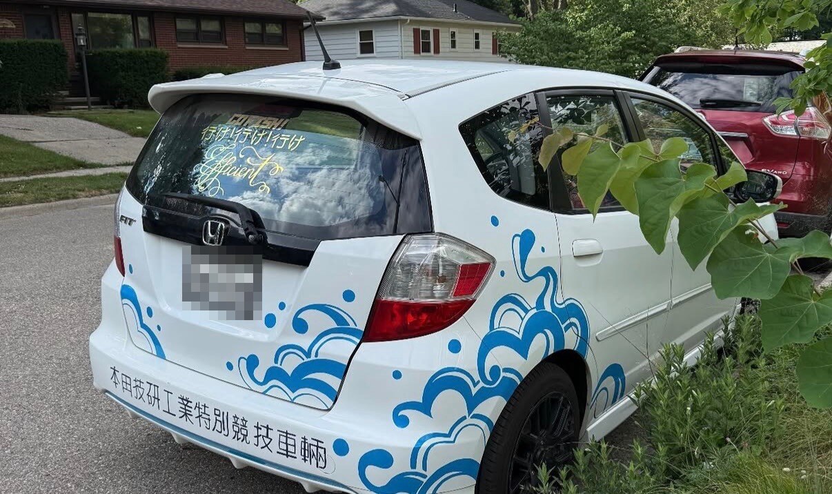 Real Honda Fit, rear three-quarter view with hand-painted blue artwork and concealed license plate